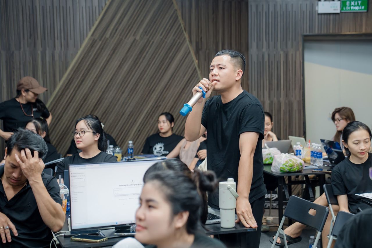 Học viên IMS mùa 2 đứng giữa các cụm bàn cầm micro phát biểu