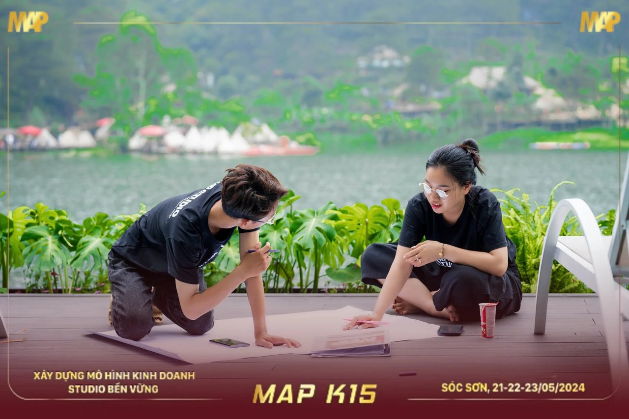 Hai học viên MAP CAMP mùa 15 quỳ trên sàn gỗ vẽ bản đồ khổ lớn