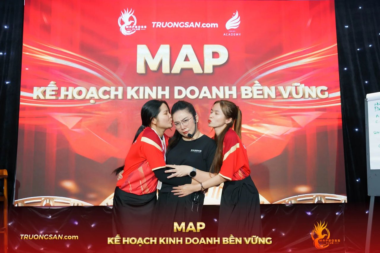 Hai học viên áo đỏ ôm hôn người đứng giữa tại MAP CAMP mùa 18