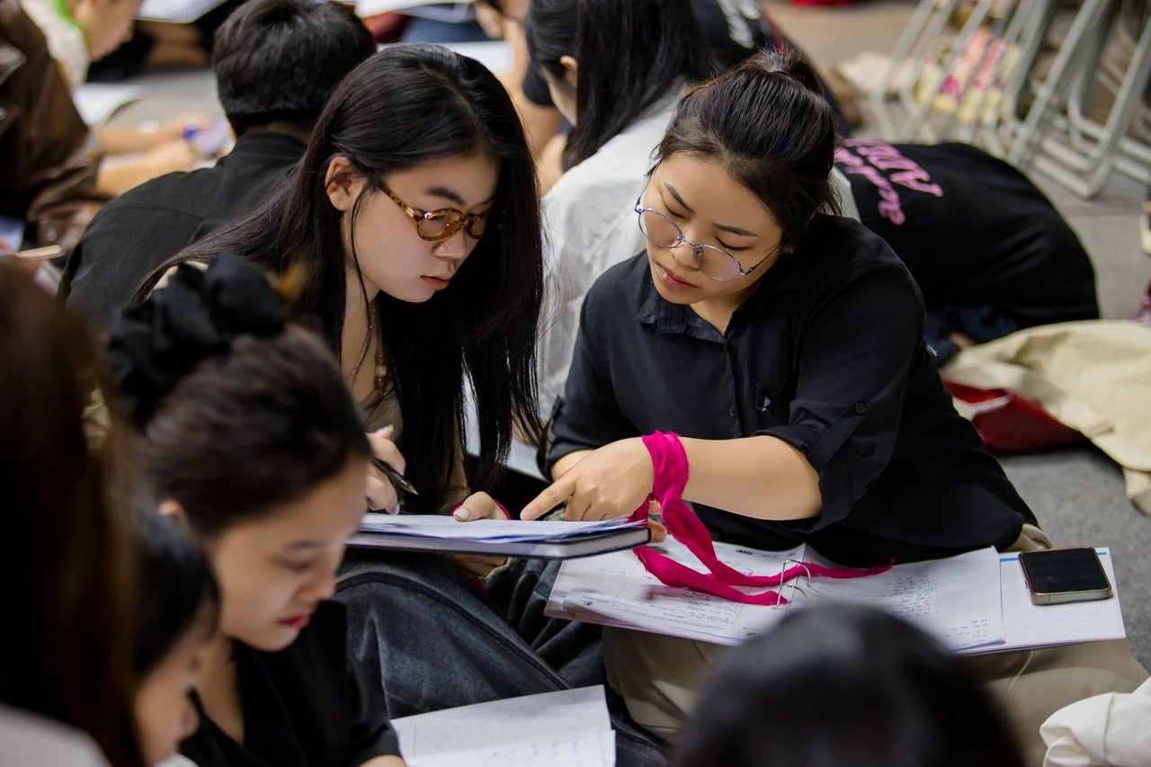 Hai học viên Sát Thủ Bán Hàng ngồi dưới sàn chăm chú làm bài