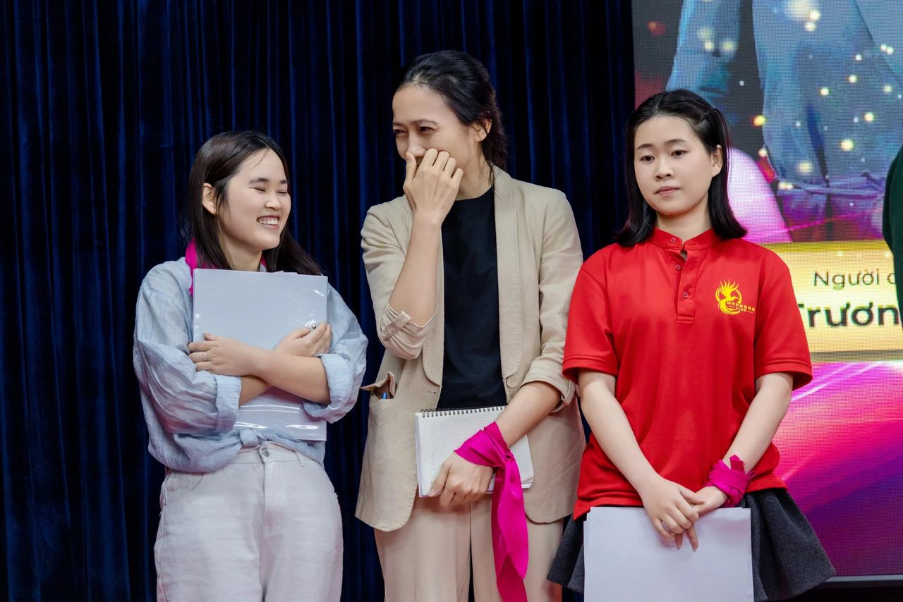 Học viên Sát Thủ Bán Hàng đưa tay che miệng khi đứng trên sân khấu