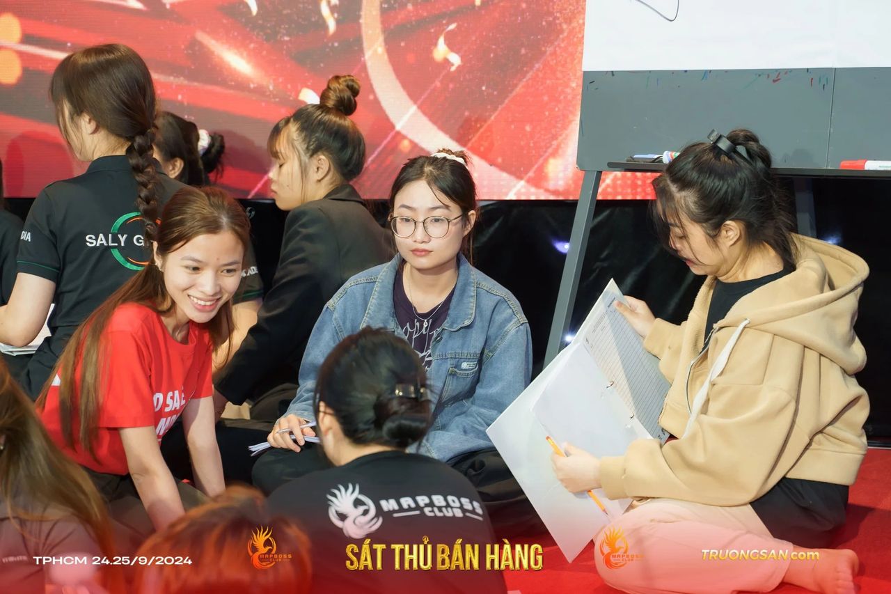 Nhóm học viên Sát Thủ Bán Hàng ngồi bệt trên thảm đỏ làm bài