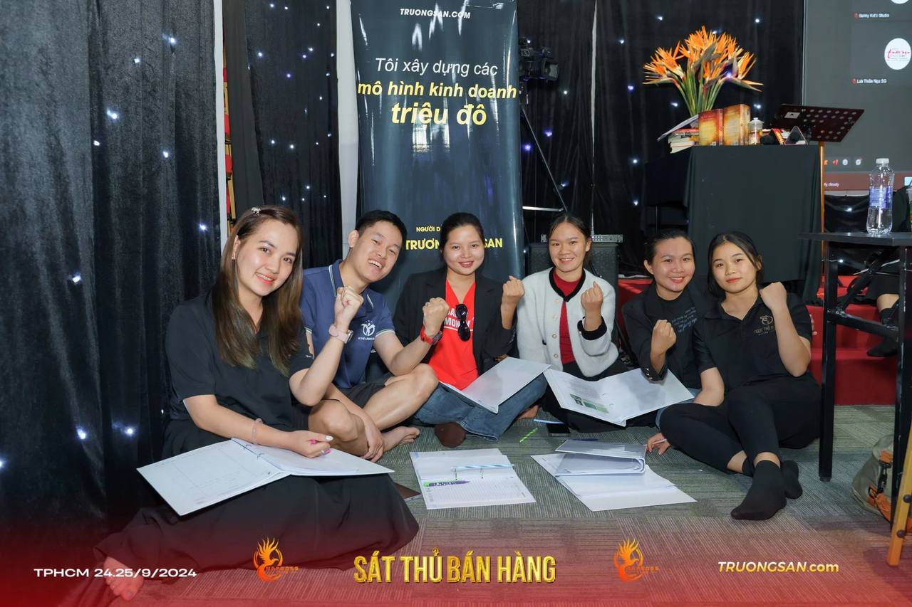 Nhóm học viên Sát Thủ Bán Hàng giơ nắm tay bên những trang bài làm