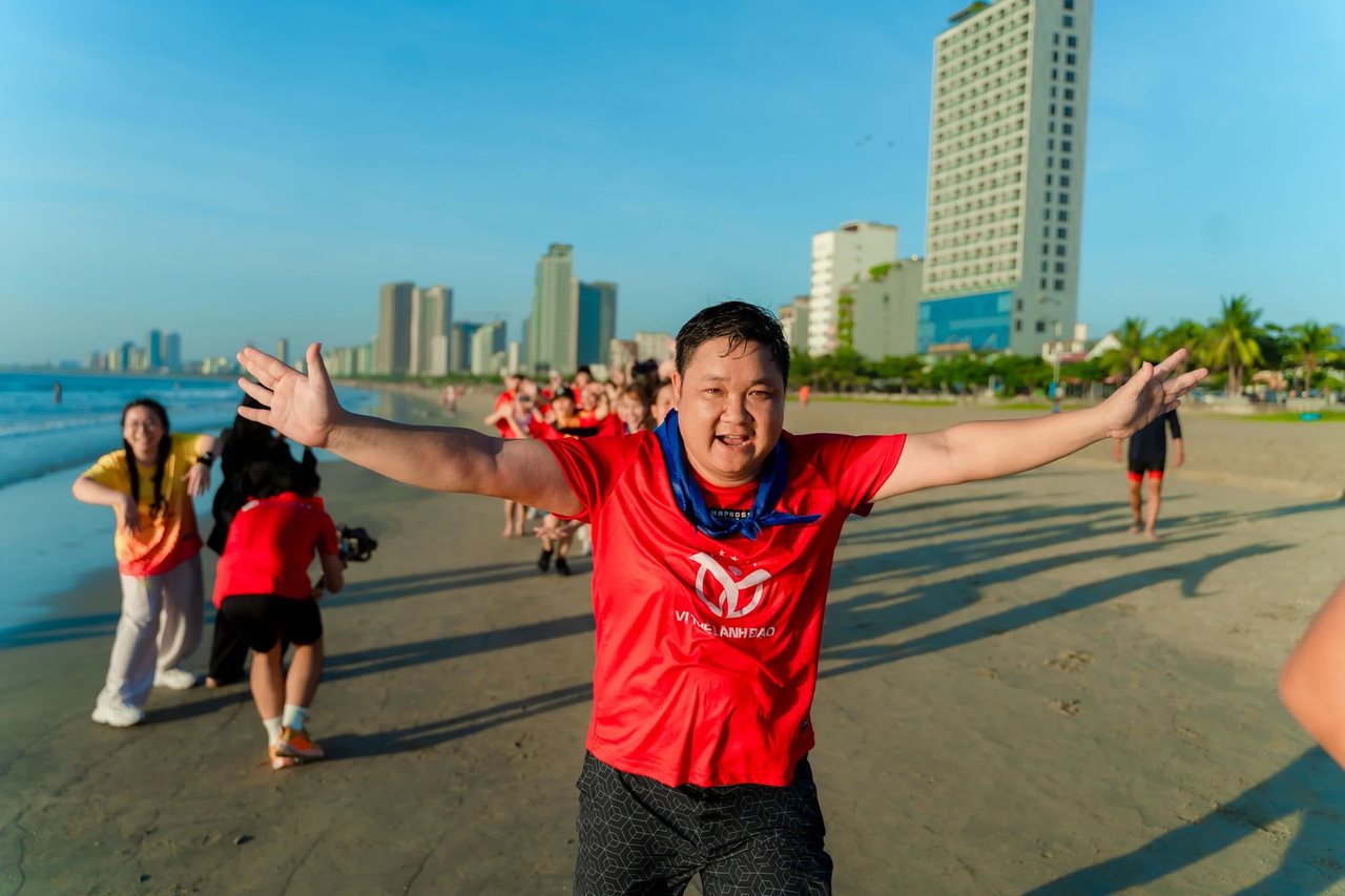 Học viên Vị Thế Lãnh Đạo mùa 2 áo đỏ dang rộng tay trên bãi biển