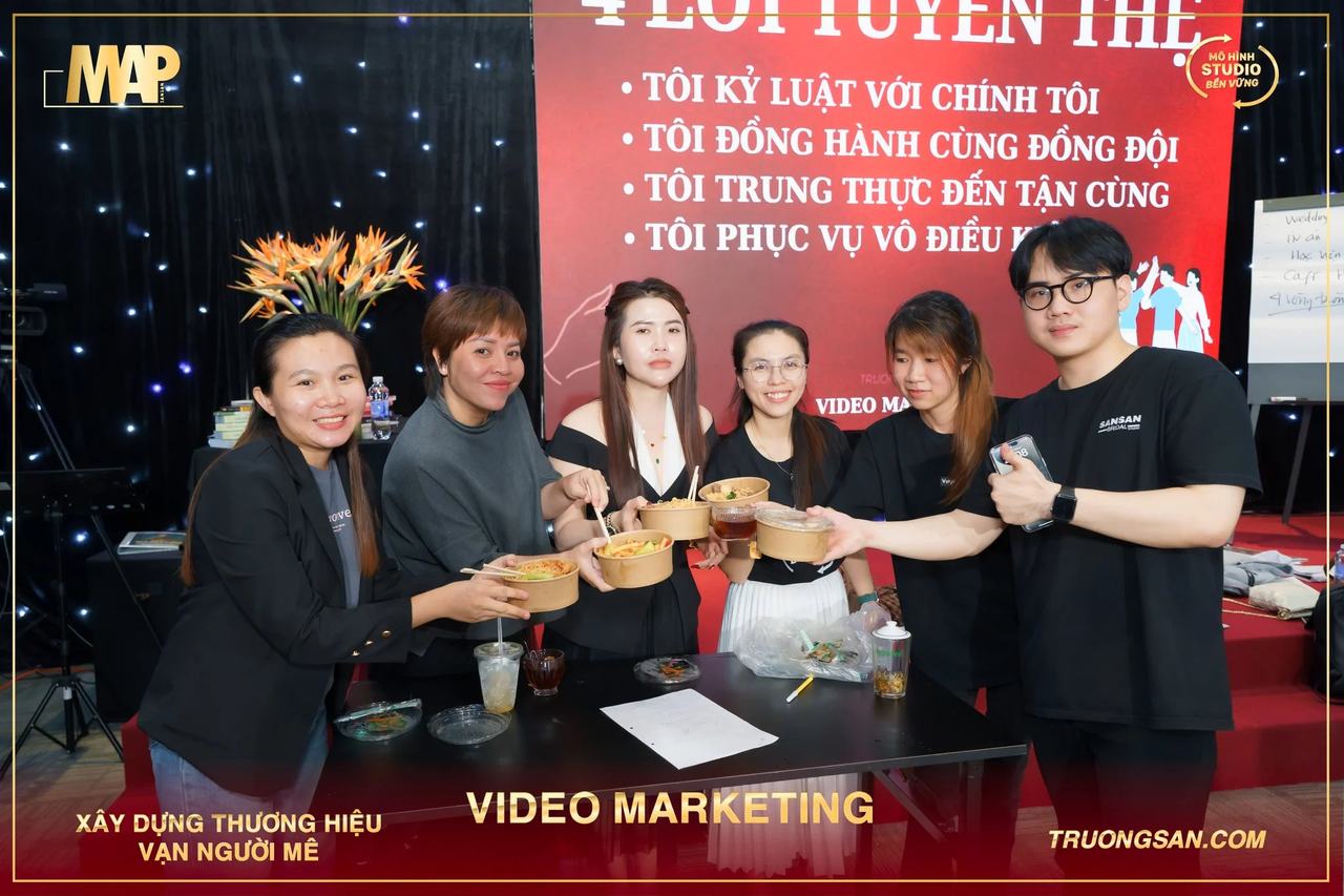 Nhóm học viên Video Marketing mùa 6 nâng bát giấy trước tấm phông lời tuyên thệ
