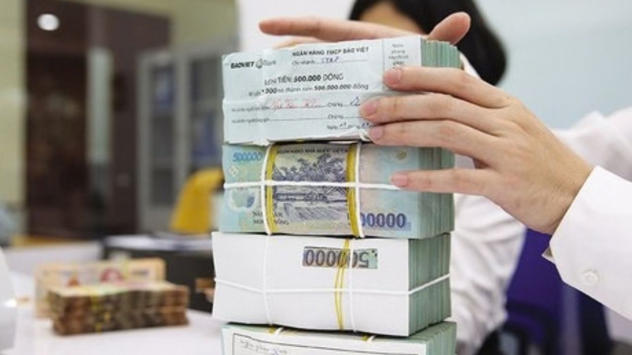Nhân viên ngân hàng kiểm đếm các bó tiền mệnh giá 500.000 đồng, minh họa nguồn vốn cho vay và chi phí vận hành trong hoạt động tín dụng, đặc biệt đối với các khoản vay nhỏ.